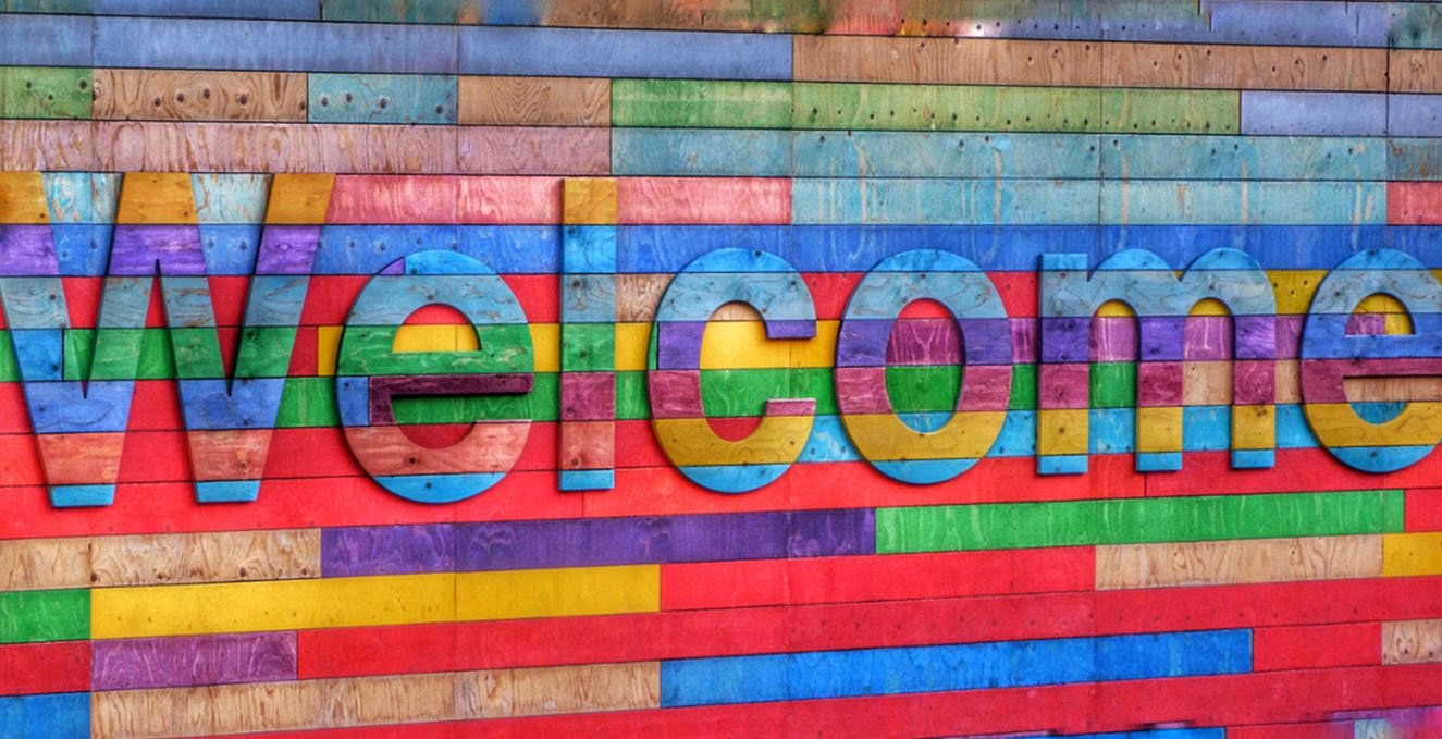 multi-color paneled fence with the word welcome