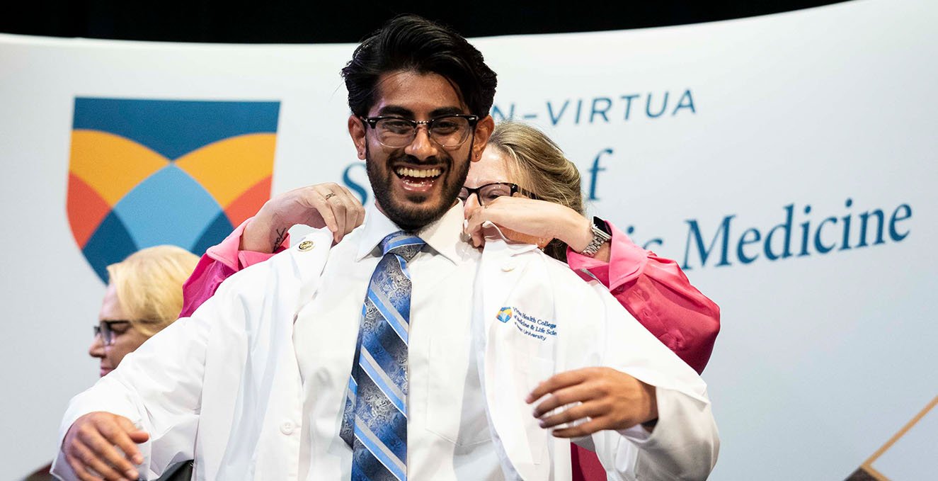 A new SOM student receives his white coat during the white coat ceremony