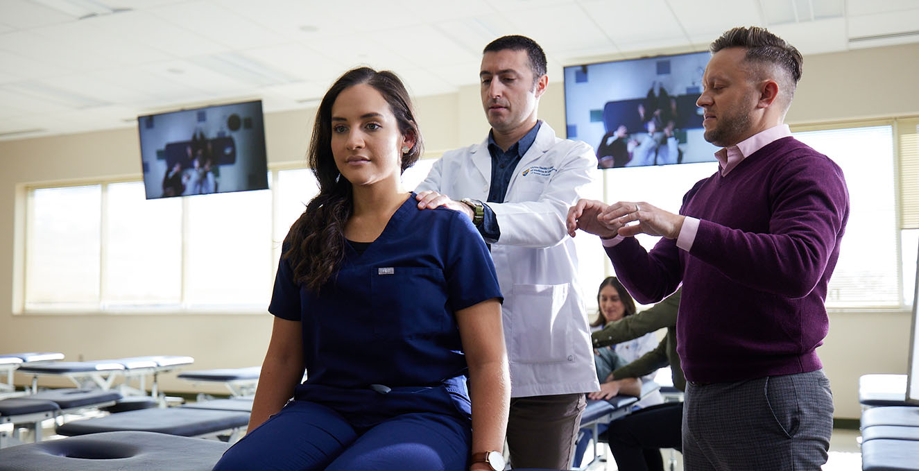 a faculty member teaches OMM techniques to two students