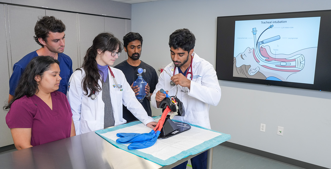 med students look on as a med students works on a procedure in the procedure room