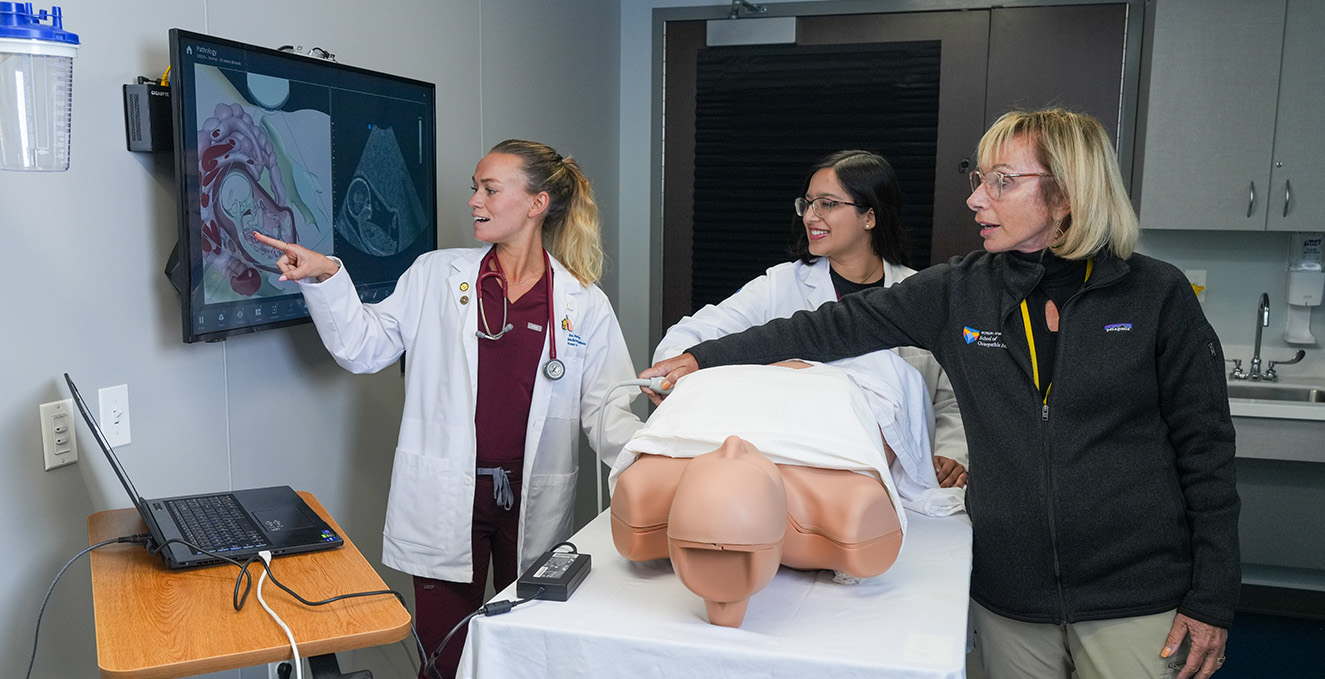 an instructor works with two medical students in the ultrasound lab at the simulation center