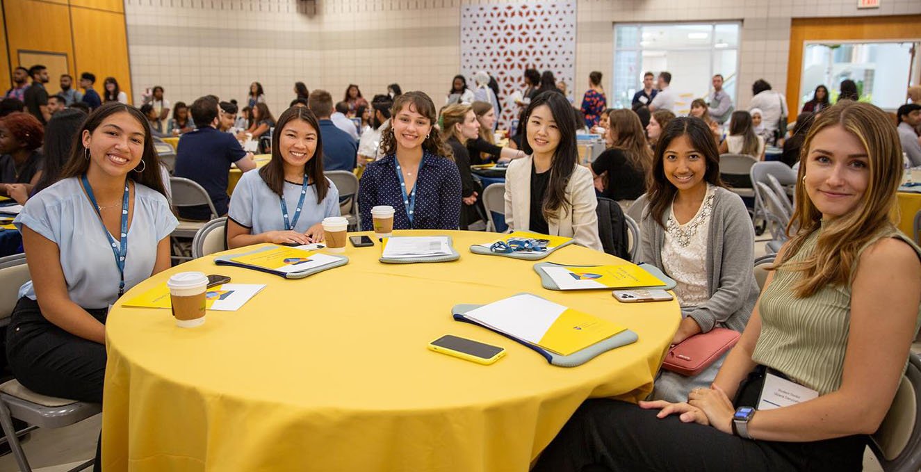 A group of SOM students sit around a table during orientation