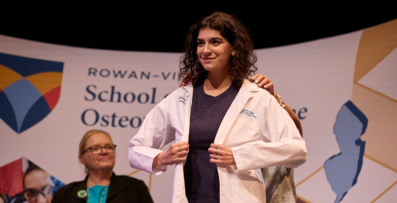 a medical student puts on her white coat during the white coat ceremony