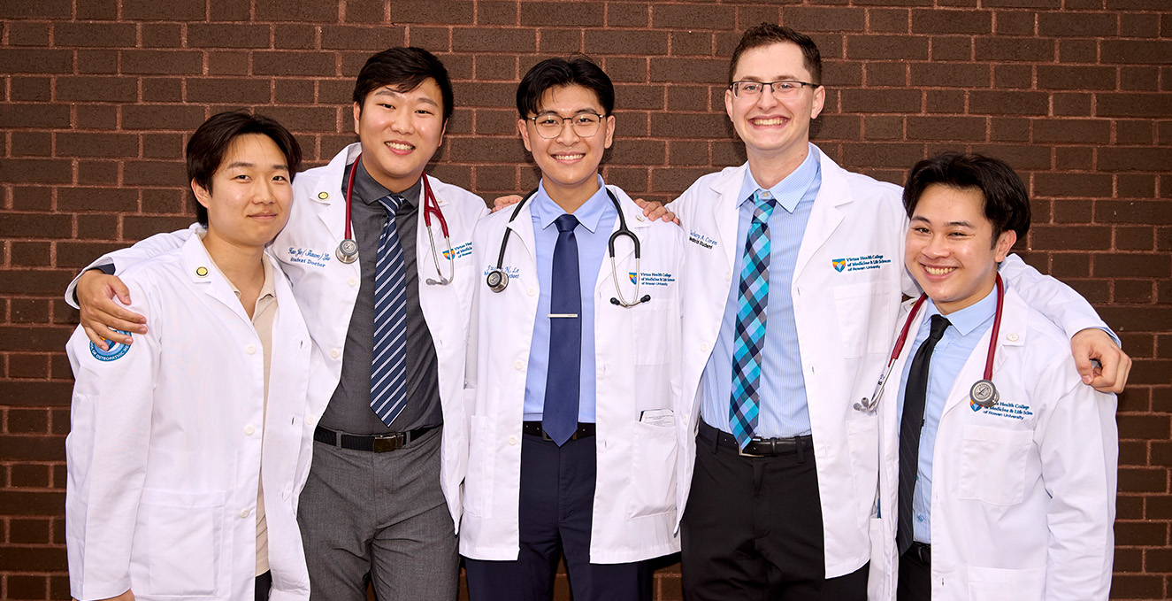 a group of medical students pose for a smile at the white coat ceremony