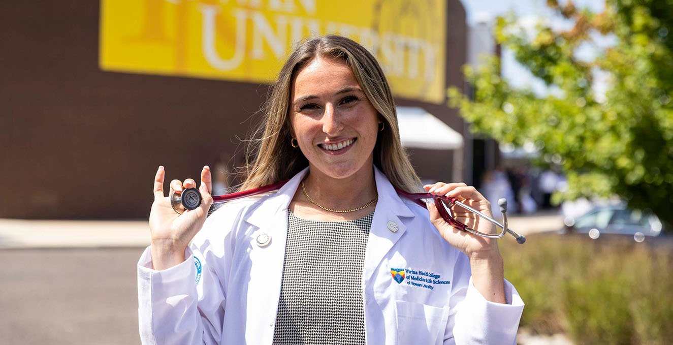 SOM student puts on her stethoscope outside of Pfleeger concert hall at the white coat ceremony