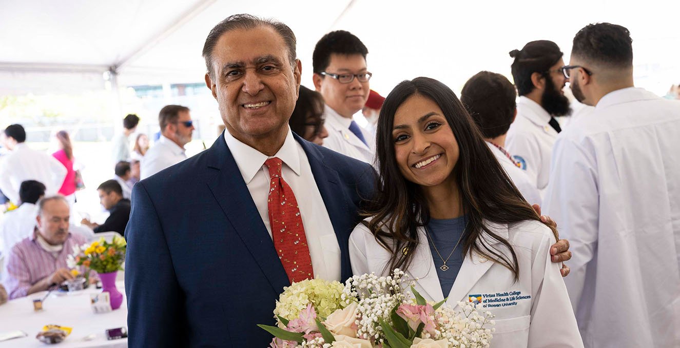 An incoming SOM student smiles and hugs her father at the white coat ceremony