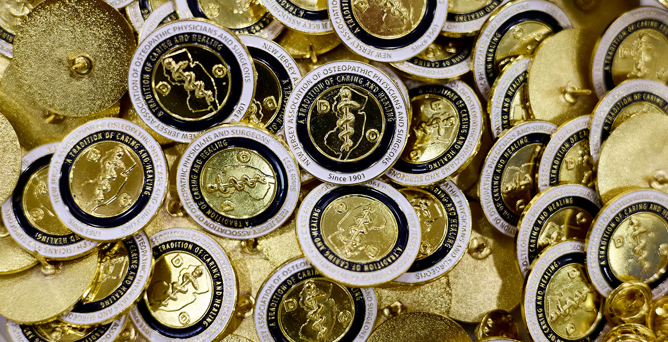 a big pile of gold and blue pins for SOM white coats