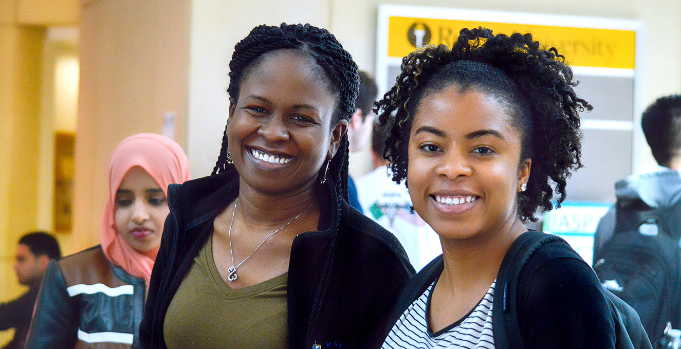 Two smiling SOM students in a social environment.