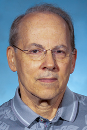 Louis Papa looks at the camera while wearing glasses and a blue golf shirt