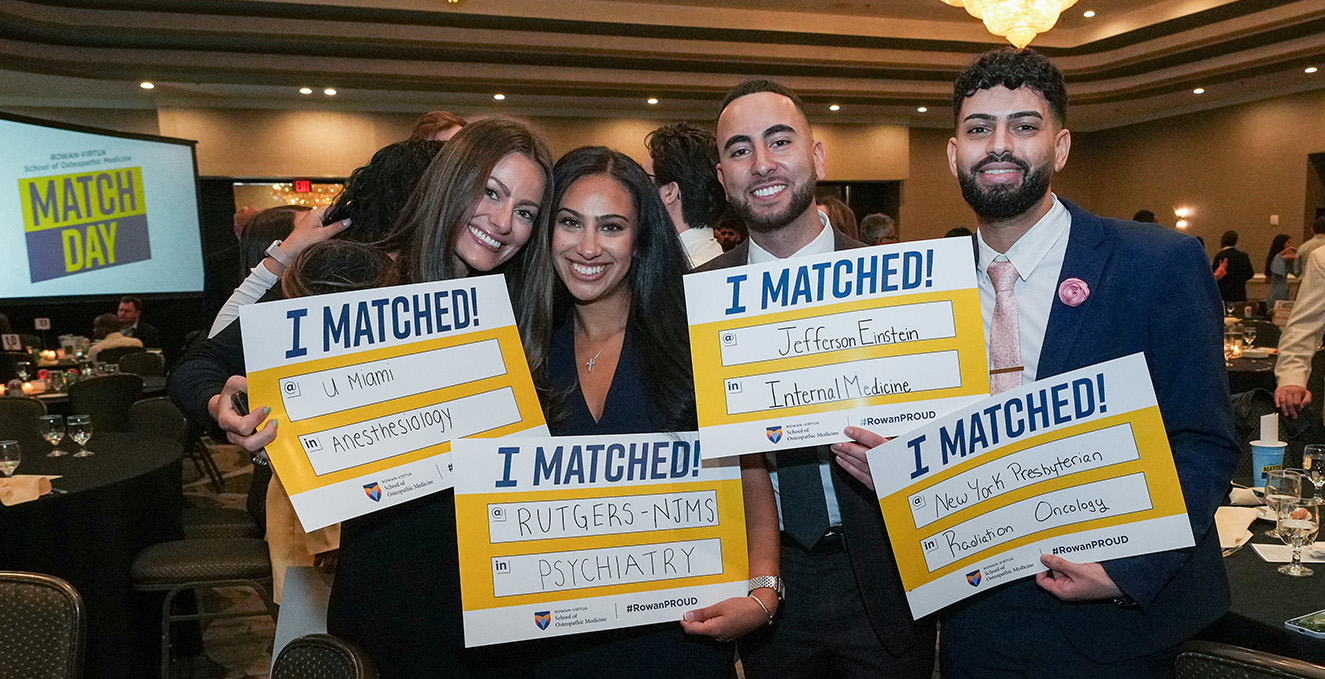 Four SOM students smile and display their Match Day signs