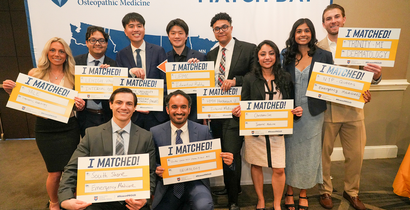 Ten fourth year SOM students hold their I Matched signs on Match Day while standing in front of a large US map