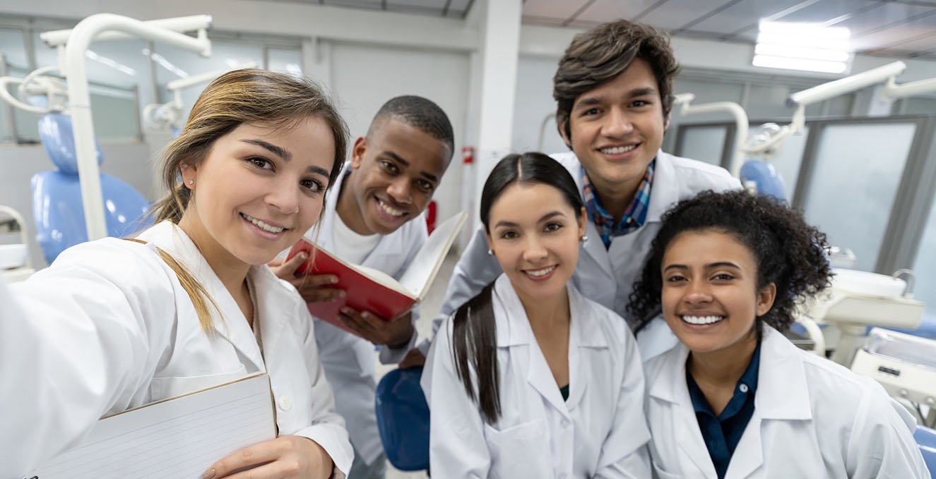 four medical students smile for a selfie in a clinical room