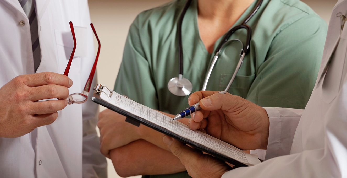 three health care professionals look over a clip board