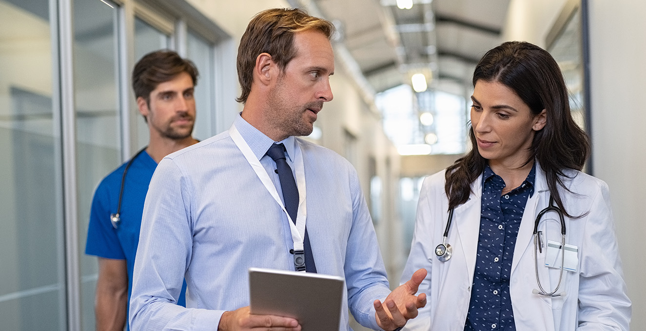 two health care providers walk and talk in a hallway