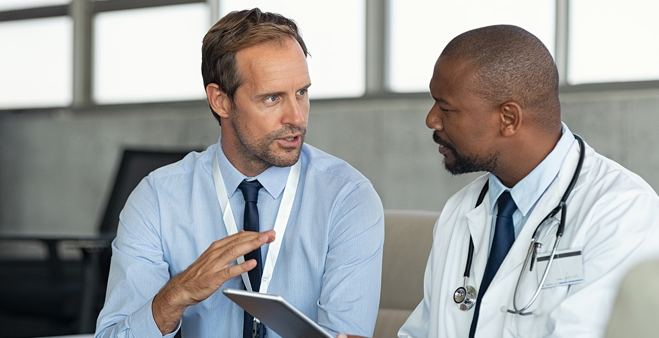 two health care workers sit and talk about something on a tablet