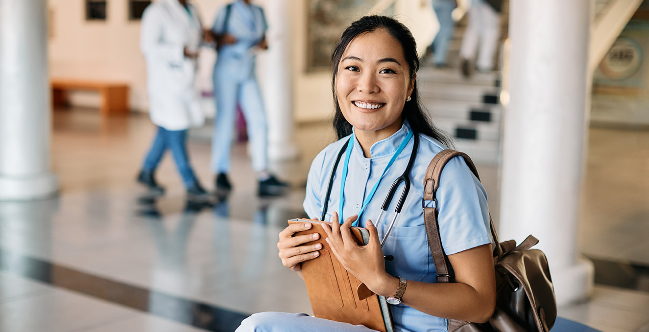 a medical student sits in a hallway and smiles at the camera