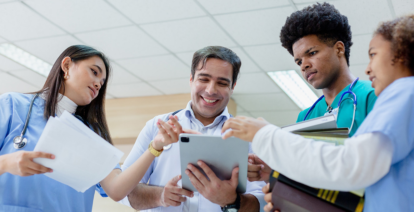 three health care students talk with a doctor in the hallway