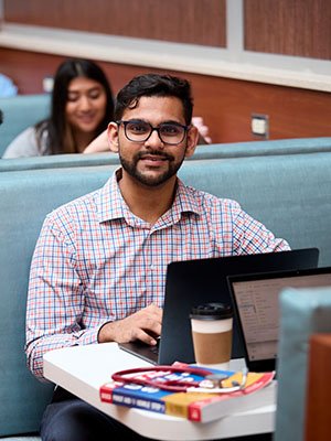 a male SOM student smiles as he studies in the cafe
