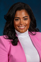 Margarita David smiles for the camera while wearing a pink suit jacket and white turtleneck