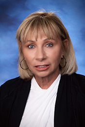 Kathleen Deiling smiles for the camera while wearing a black turtleneck and a long, gold necklace