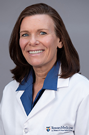 Wendy Aita smiles at the camera while wearing a blue shirt and her white coat