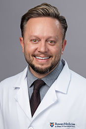 James Bailey smiles at the camera while wearing his white coat and a tie