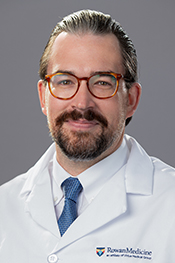 Nils Brolis smiles at the camera while wearing his white coat