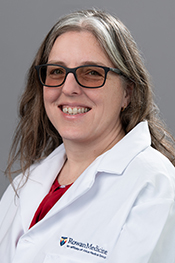 Alison Mancuso smiles at the camera while wearing a red shirt, her glasses and whitecoat