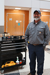 Sonny Brodbeck stands next to a rolling workbench with a level sitting on top