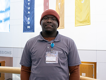 Nate Huntley, wearing brown and a brown beanie, stands on the landing of the stairs in the SOM Academic Center