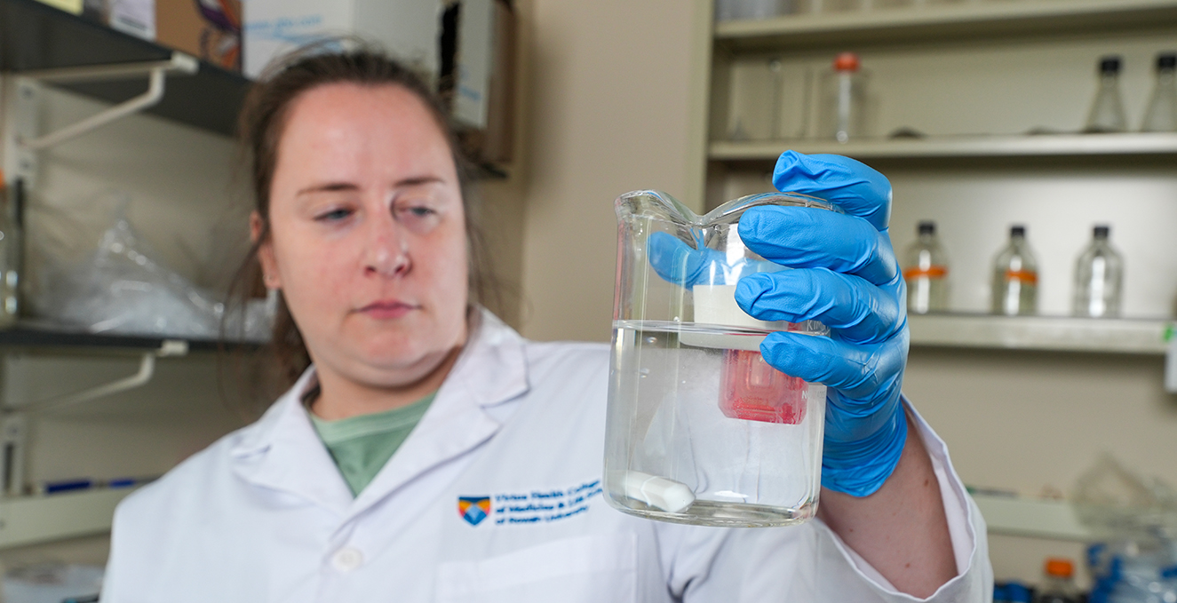 a doctoral student researcher looks at a liquid in a large beaker