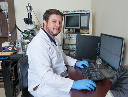 Dr. Dan Chandler smiles while working at a monitor in his lab