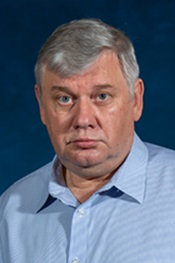 Mikhail Anikin looks at the camera while wearing a light blue shirt