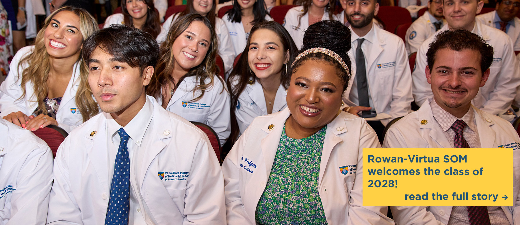 The class of 2028 smiles while sitting in the auditorium during the SOM White Coat Ceremony